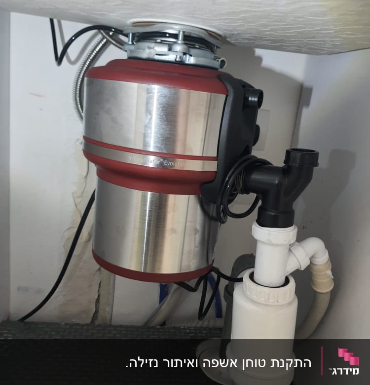 מכשיר טוחן אשפה מתחת לכיור עם צינורות חיבור